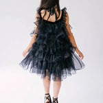 A second back view of a woman wearing a black puff dress in black platform heels.