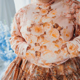Close up view of the twilight bloom pullover hoodie, worn by a plus size model wearing with a blurred background.