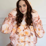 Woman wearing a floral print pullover hoodie against a plain background