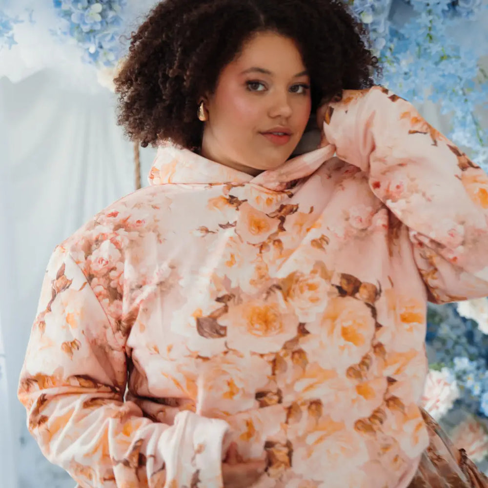 A woman wearing a an oversized floral pullover hoodie.