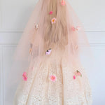 Back view of the Secret Garden Floral Veil featuring layered peach tulle and vibrant pink flowers. Worn by a woman in a white lace dress.