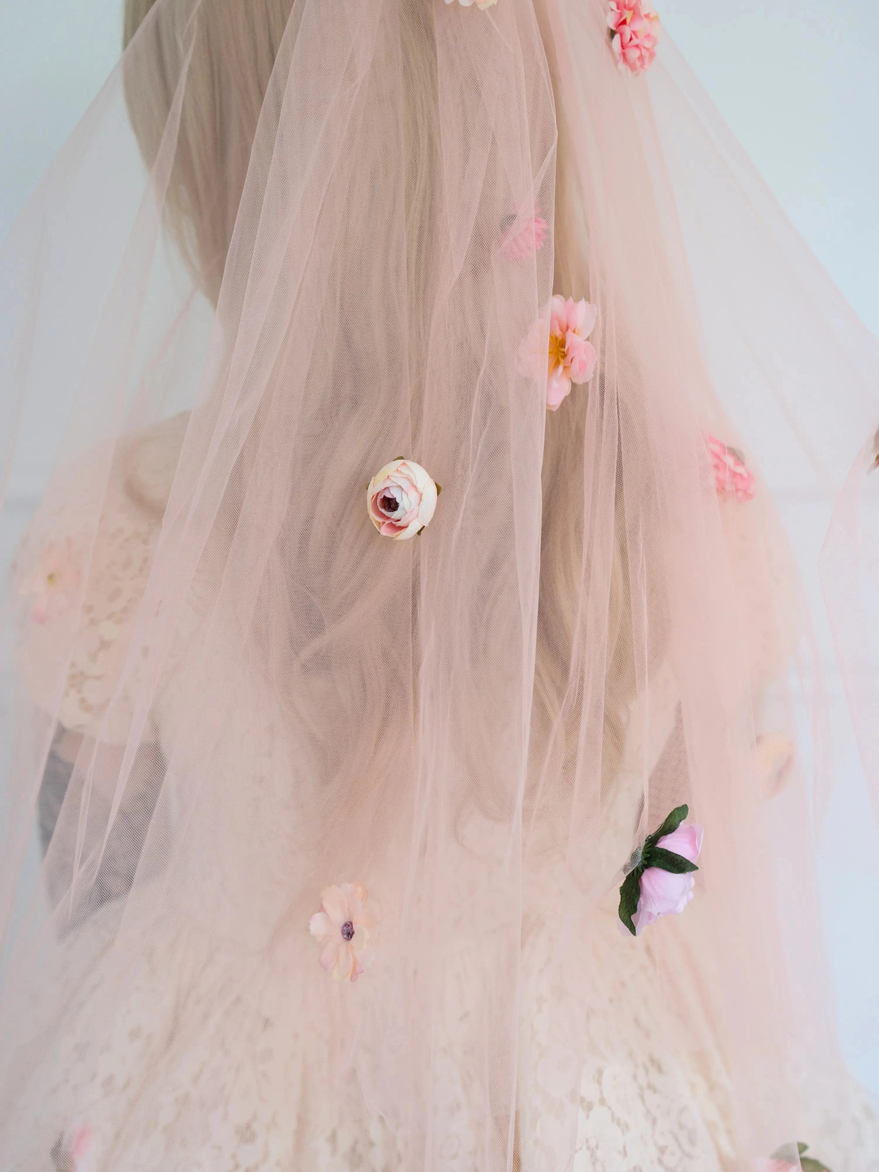 Floral wedding veil with 3D hand sewn decorations worn by a woman.