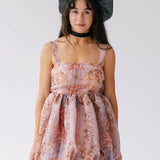 A woman wearing a floral dress with a large black hair bow on a white background