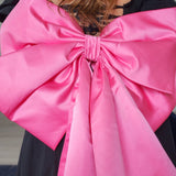 Bright pink satin bow on dark garment for The Grand Bow Sash, perfect for bow lovers