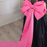 Bright pink oversized bow on black dress from The Grand Bow Sash for bow lovers