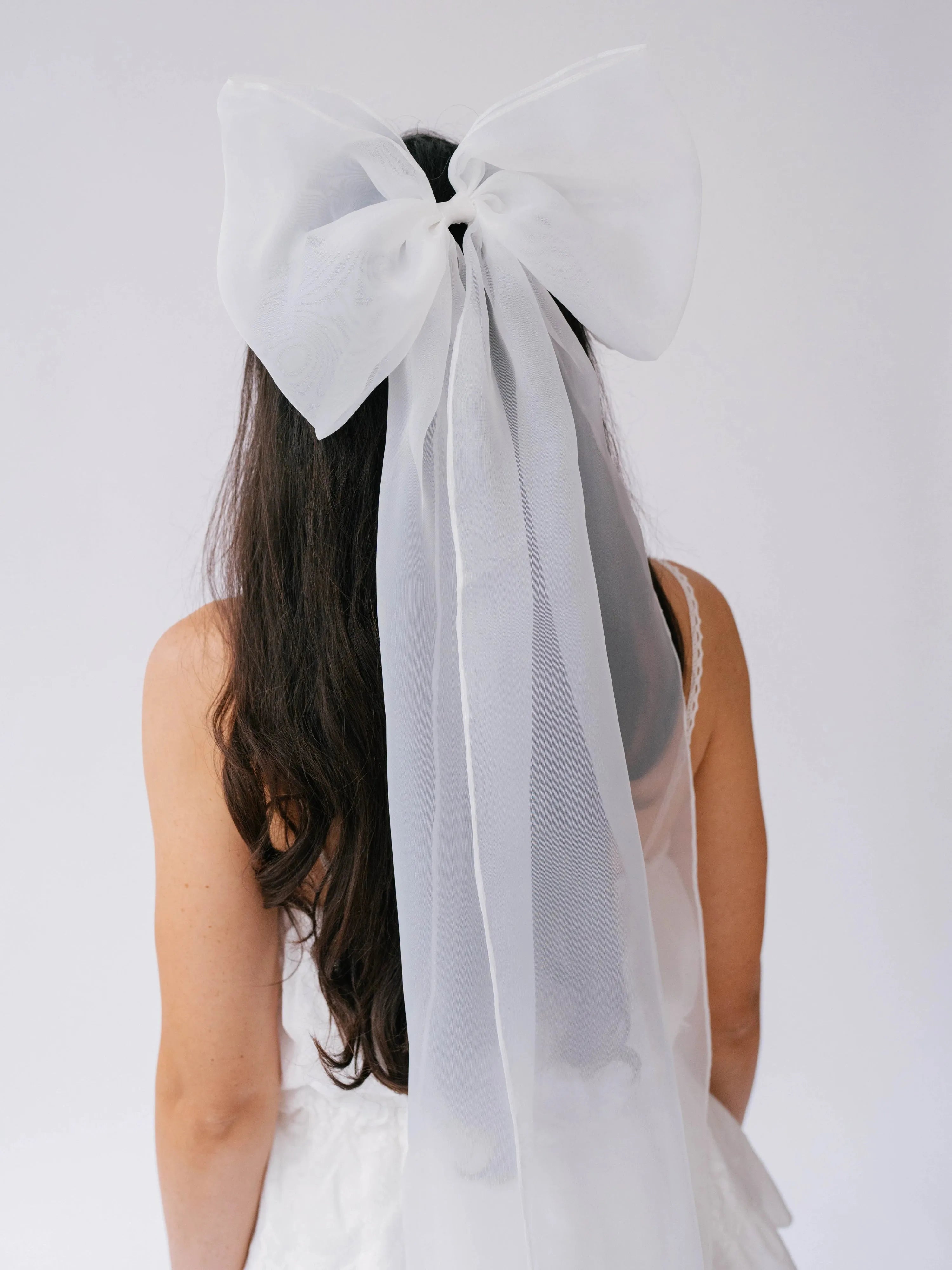 Close-up of a white bridal hair bow in a woman's hair.