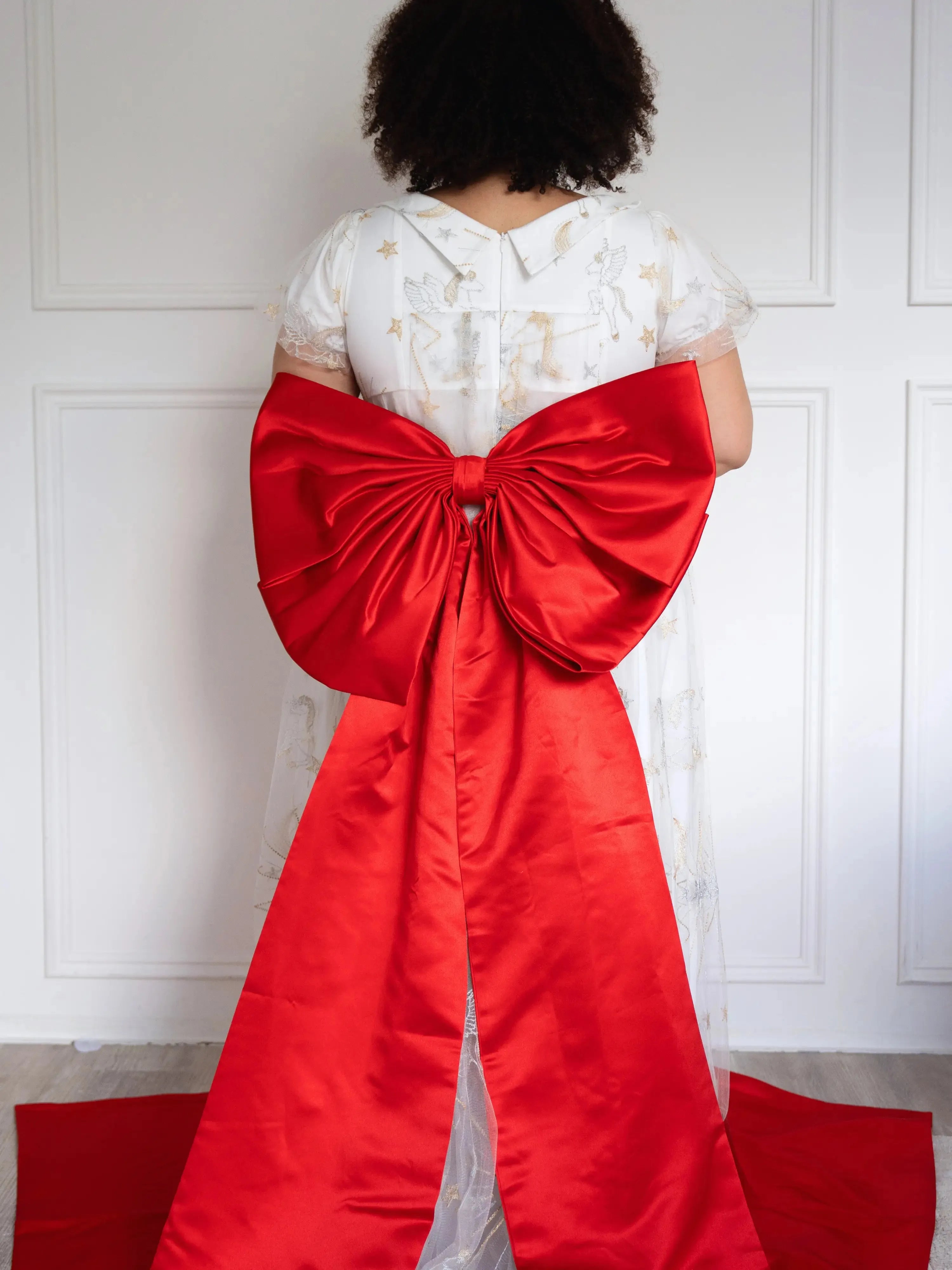 Back view of The Holiday Red Grand Bow Belt on a plus-sized model showing it's long satin tails.
