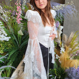 A woman in a white corset top, showcasing the intricate lace on long sleeves.