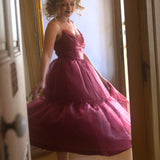 A woman in a red organza midi dress is standing in a doorway.