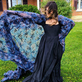 Woman in a flowing black dress showcasing the High Priestess Cape with a blue shawl