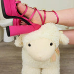 Hot Pink Platform Heels worn by woman resting her feet on a cute white sheep toy rocking chair.