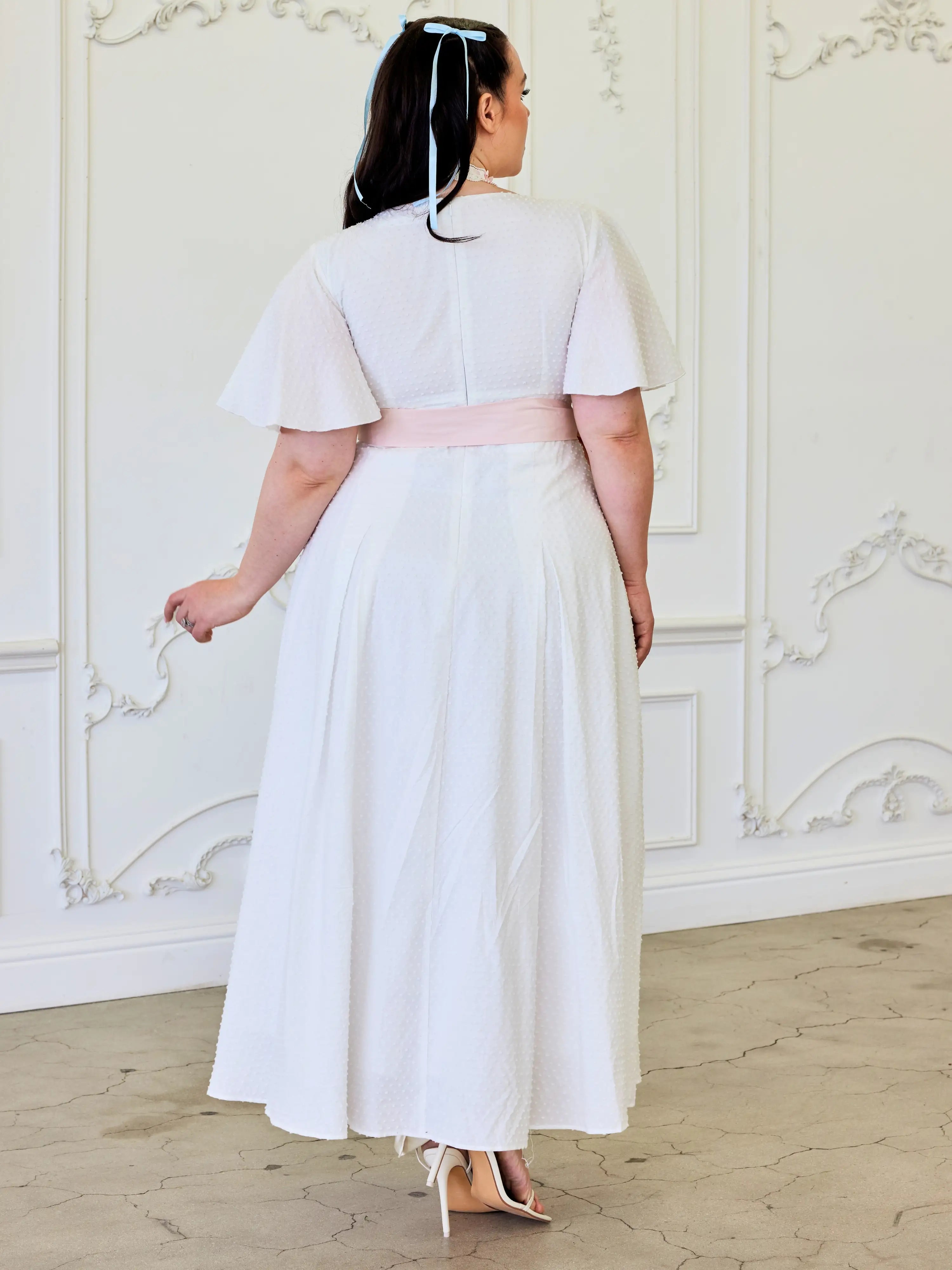 Woman in Ivory Cloud Midi Dress with flutter sleeves and pink waistband, back view