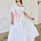 White off-shoulder Ivory Cloud Midi Dress with pink bow accent and flared skirt