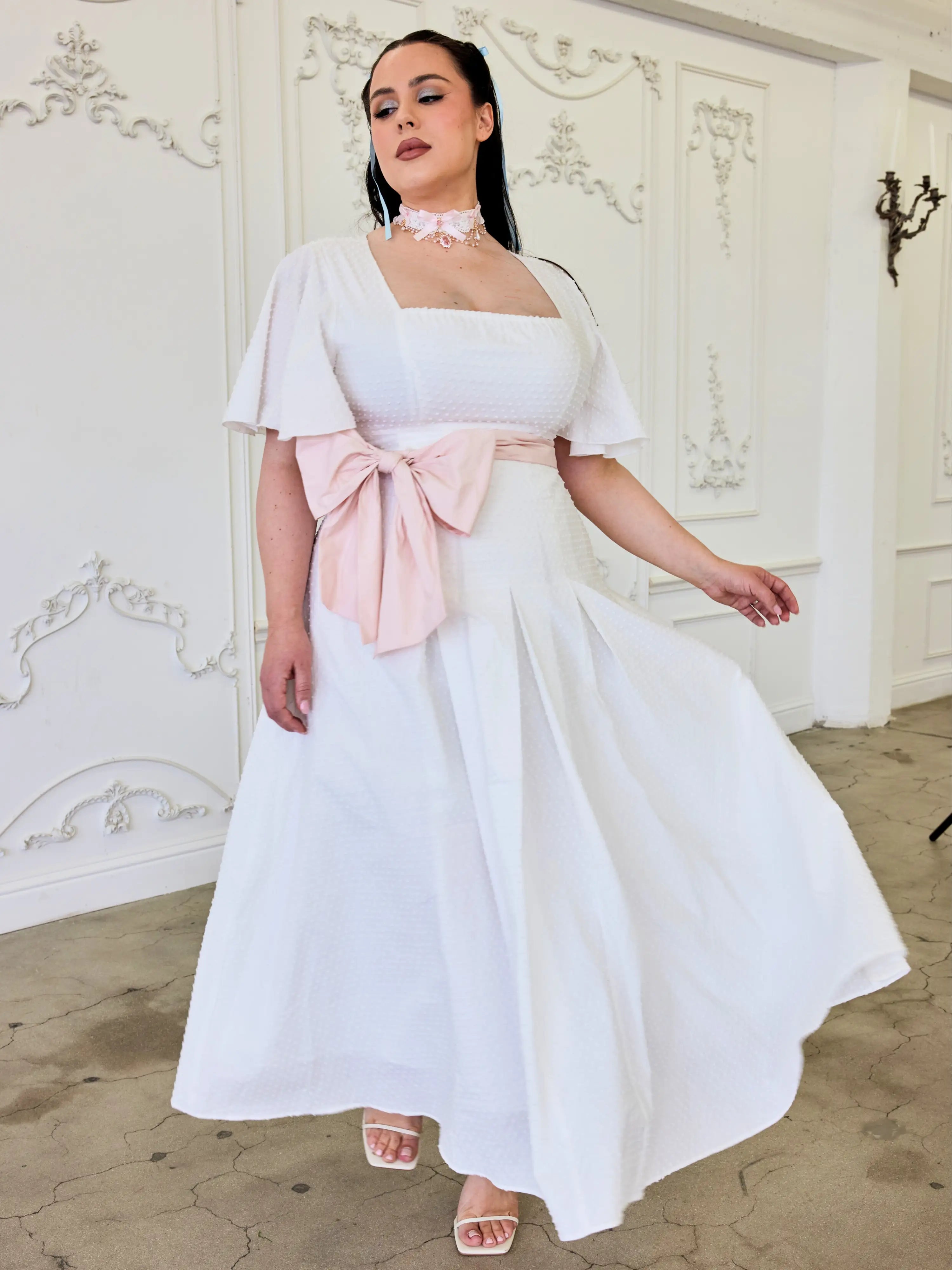 White off-shoulder Ivory Cloud Midi Dress with pink bow accent and flared skirt