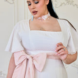 Woman in a white dress with a pink bow sash from the Ivory Cloud Midi Dress collection