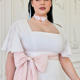 Woman in a white off-shoulder top featuring a pink bow accent on the Ivory Cloud Midi Dress