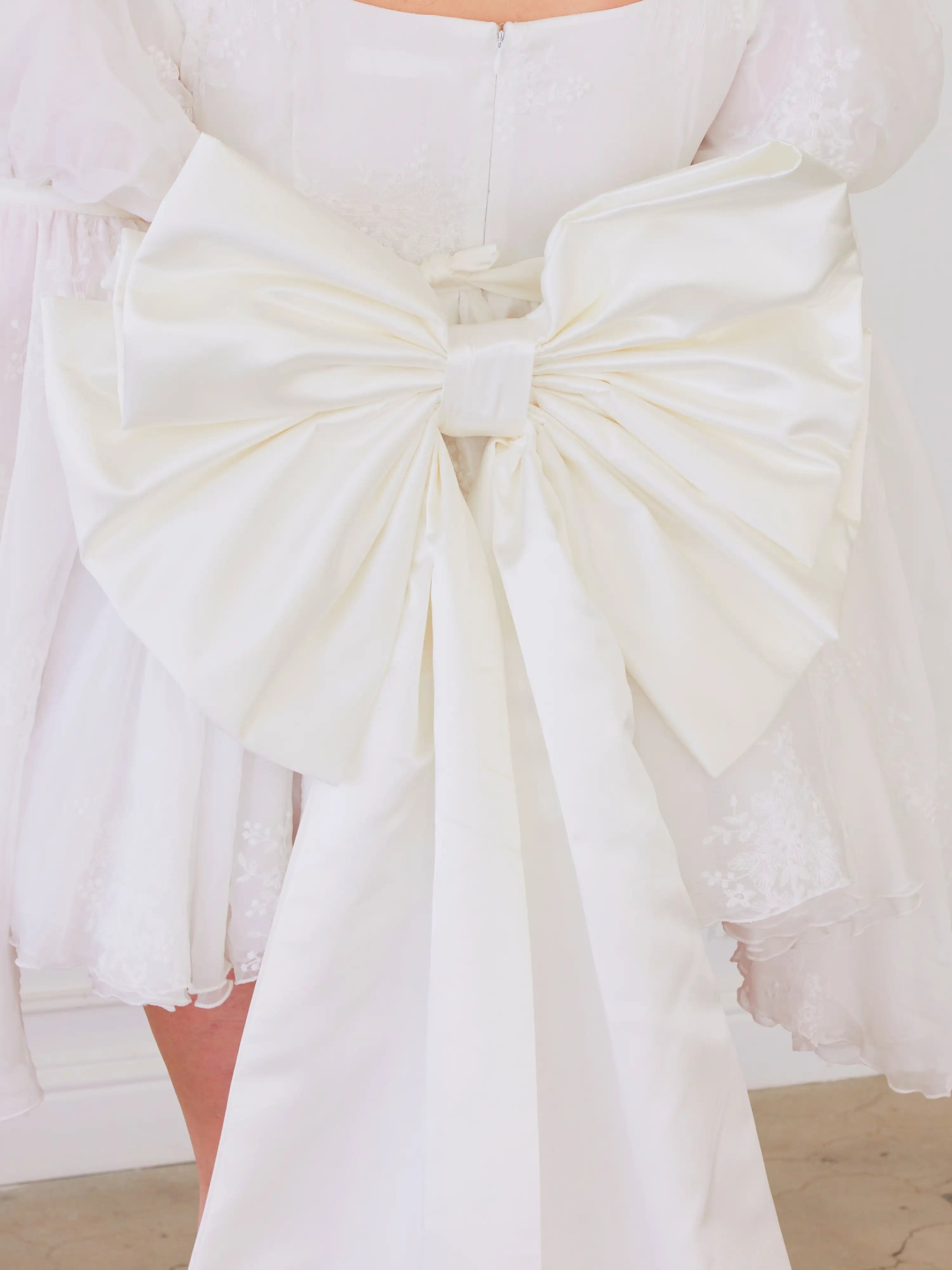 White fabric bow on The Ivory Grand Bow Sash embodies whimsical elegance