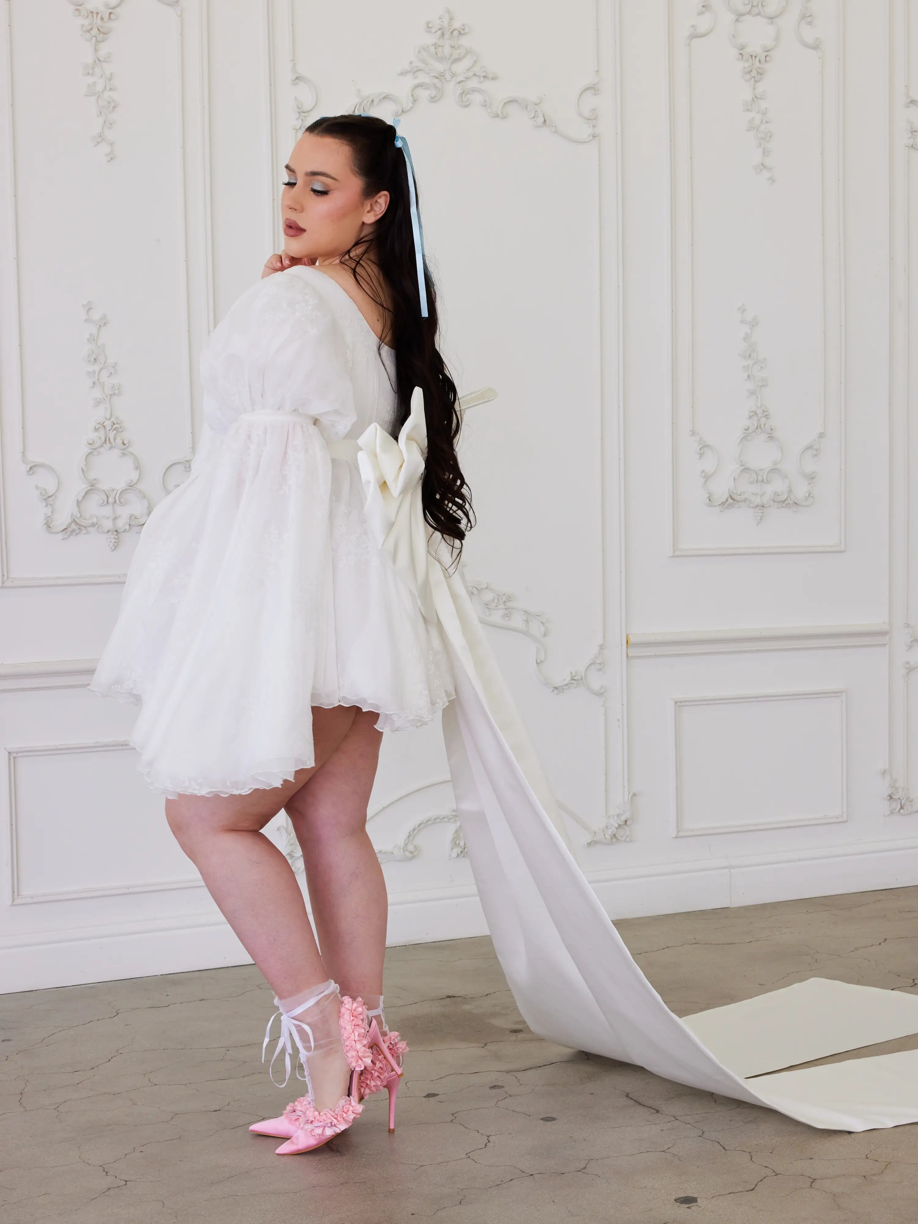 White short wedding dress with long train and puffy sleeves, showcasing whimsical elegance with a Grand Bow Sash