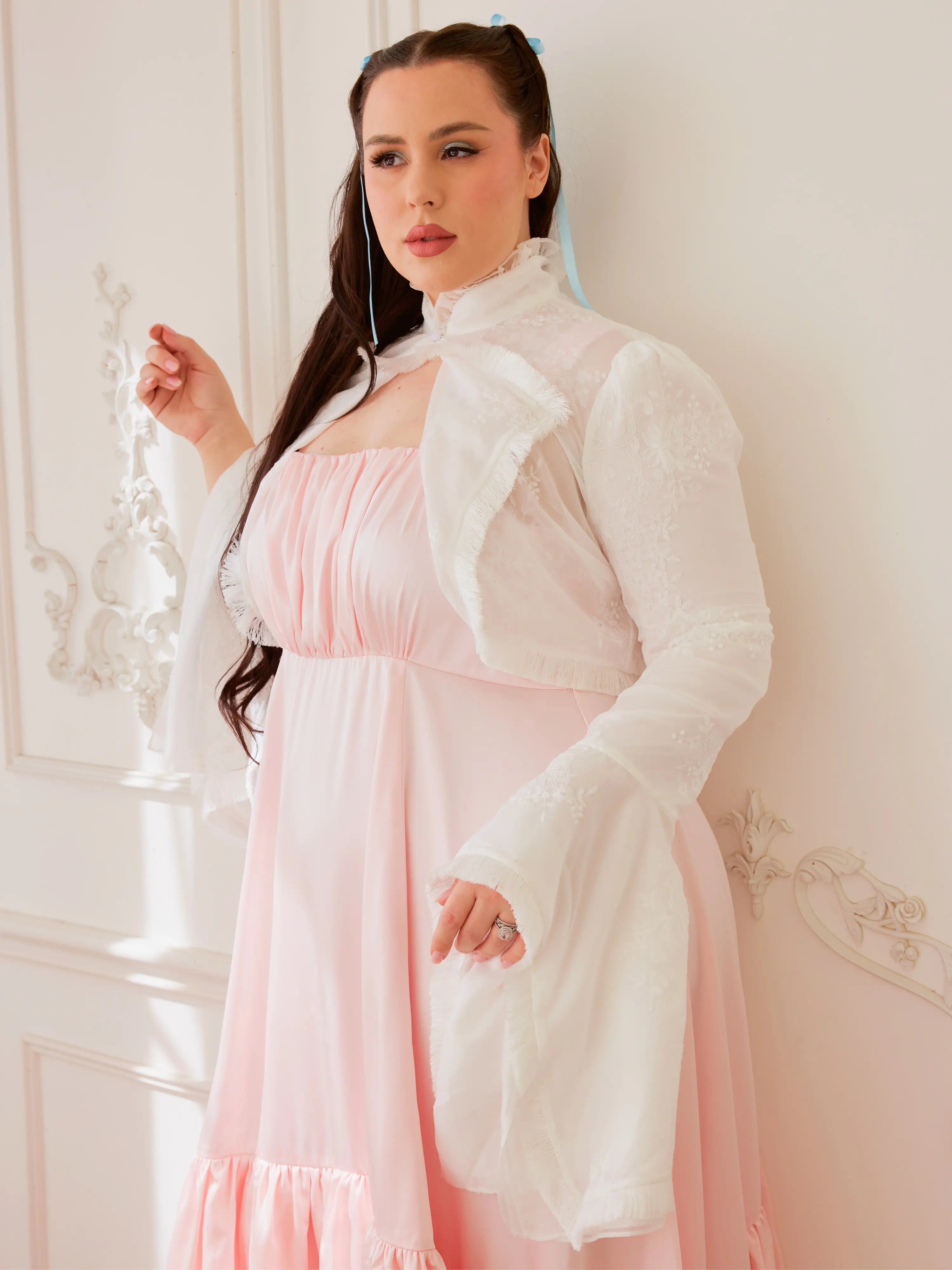 Woman in a white coat over a pink dress showcasing the Lady Elizabeth Bolero