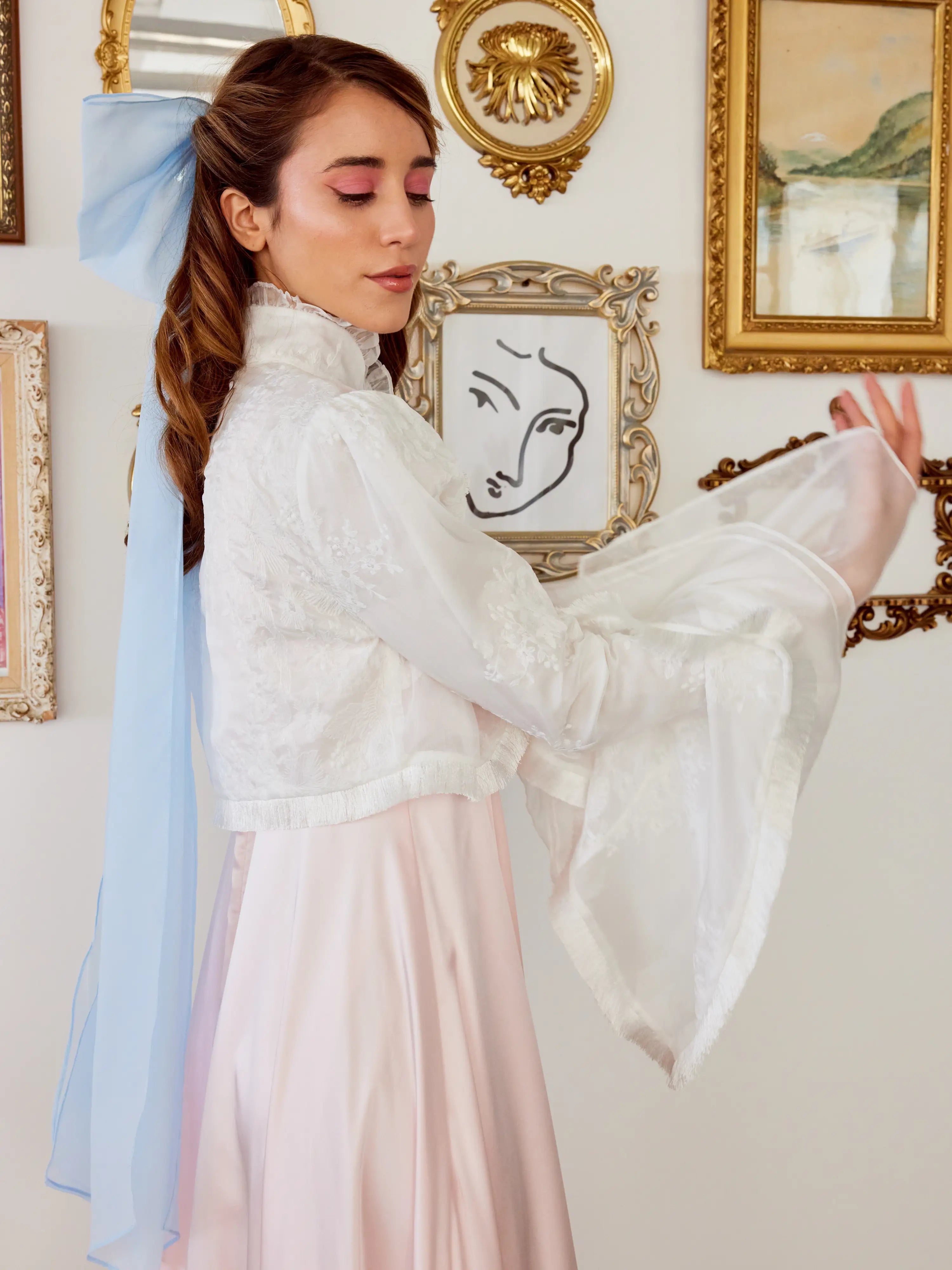 Woman wearing The Ivory Lady Elizabeth Bolero Jacket in front of framed artwork