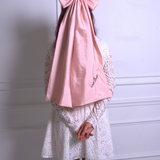 A woman wearing Ivory Sheep's Dolls Revolt Pink Hair Bow with a white lace mini dress on a white background.