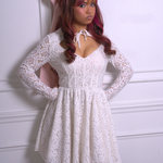 A woman wearing Ivory Sheep's Dolls Revolt Pink Hair Bow paired with a white lace dress against a white wall.