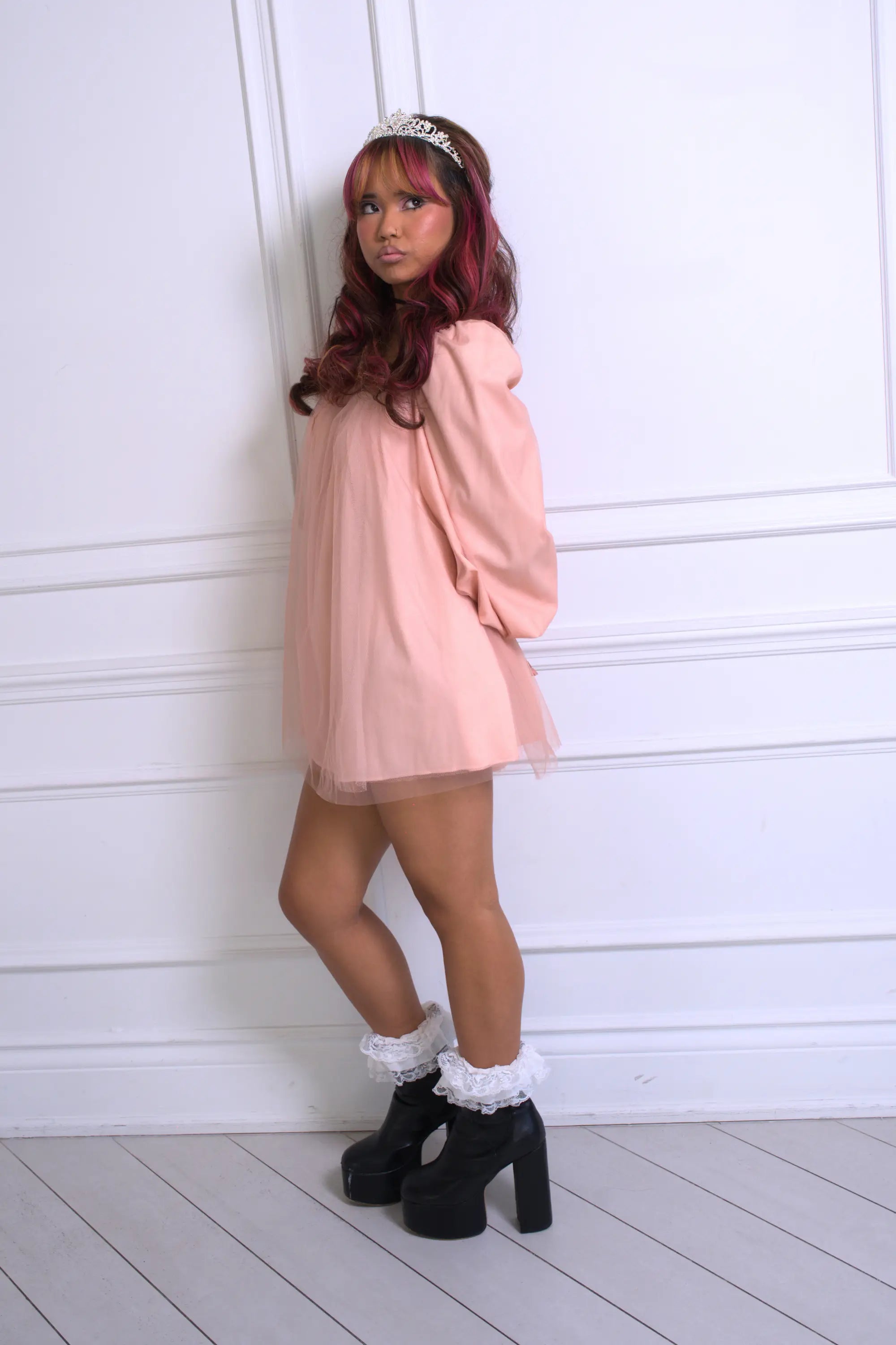 A woman wearing Ivory Sheep's Fawn Tulle Mini Dress standing against a white backdrop, showing the side view.