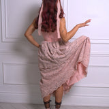 A woman wearing a pink floral dress with a hood against a white paneled wall.