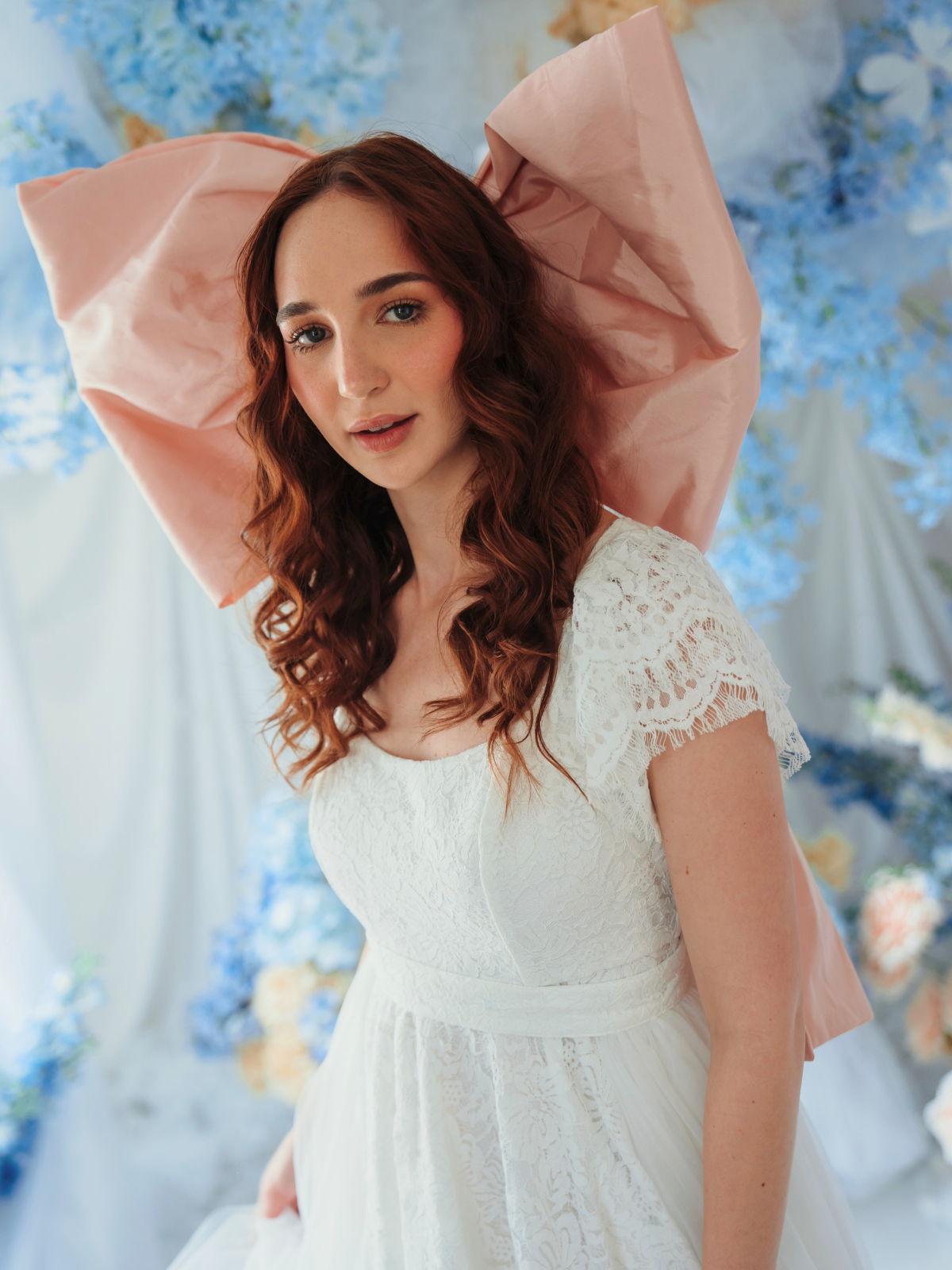 A woman in Ivory Sheep's Baby Antoinette Pink Grand Hair Bow against a floral background.