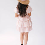 A woman wearing Ivory Sheep's Leighton Pink Cotton Mini Dress and straw hat on a white background.