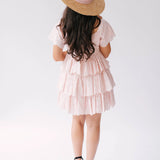 A woman wearing Ivory Sheep's Leighton Pink Cotton Mini Dress and straw hat on a white background.