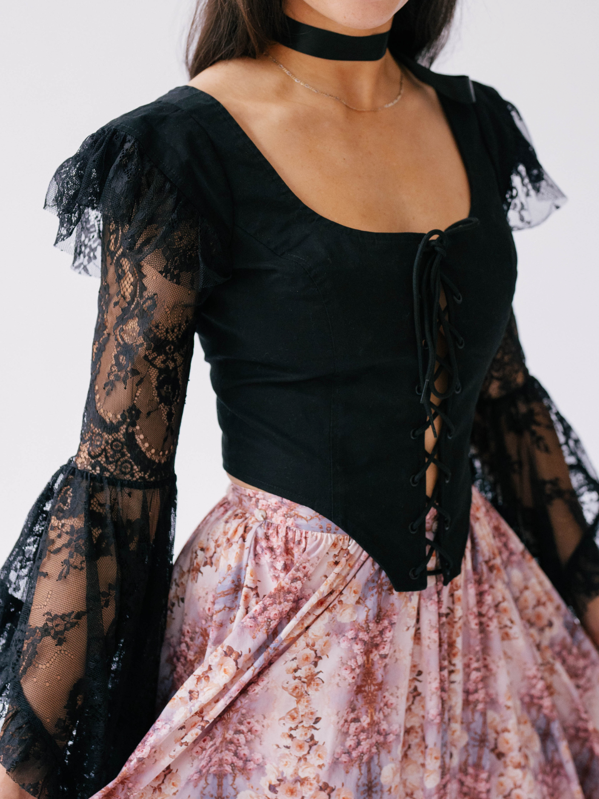 A woman in Ivory Sheep's Guinevere's corset top with a floral printed skirt on a plain background.