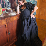 Woman in The Josephine Gown with classic puff sleeves leaning against wooden cabinet