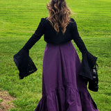 Woman in a black top and purple skirt showcasing the Lady Elizabeth jacket on grass