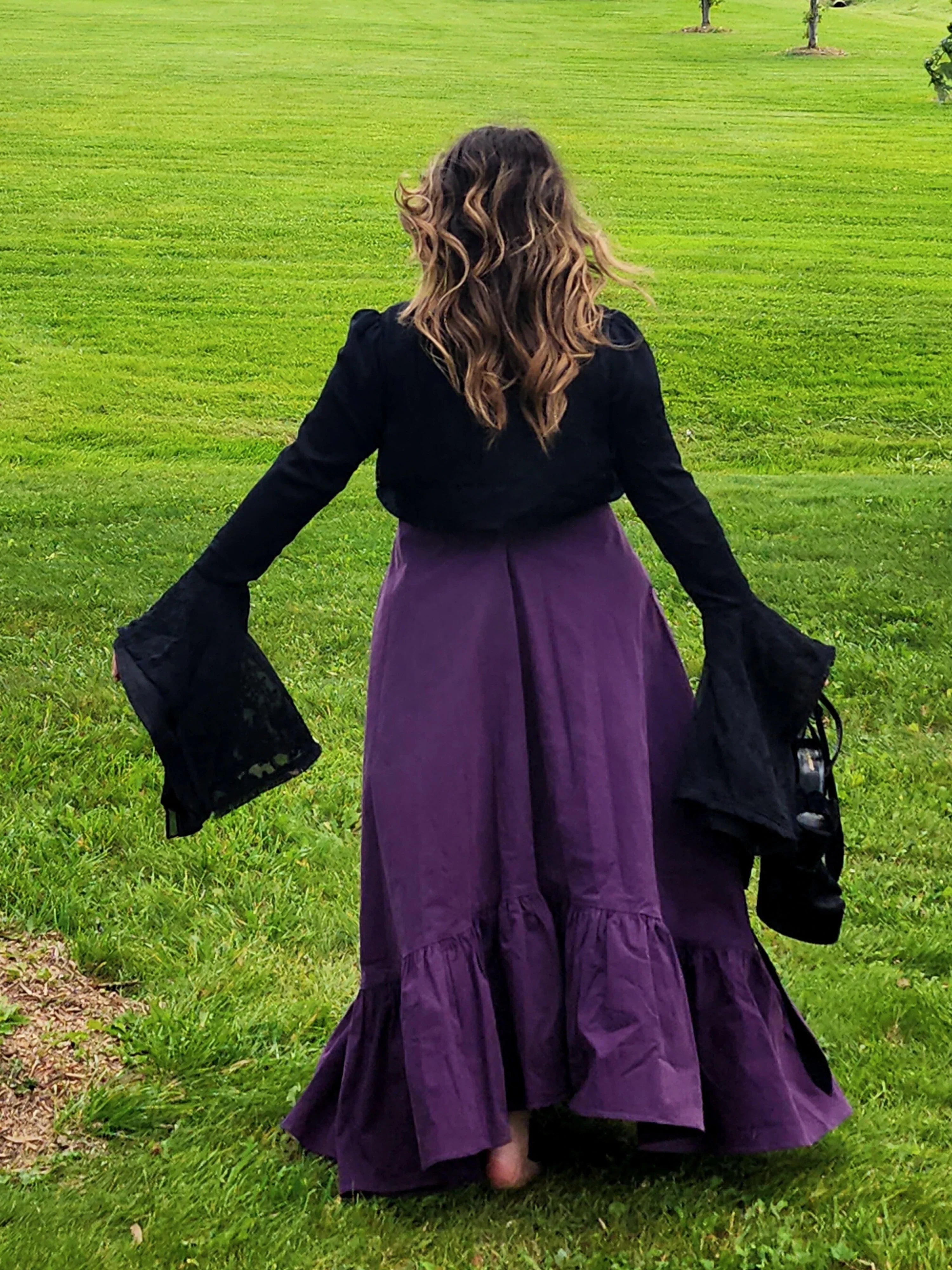 Woman in a black top and purple skirt showcasing the Lady Elizabeth jacket on grass