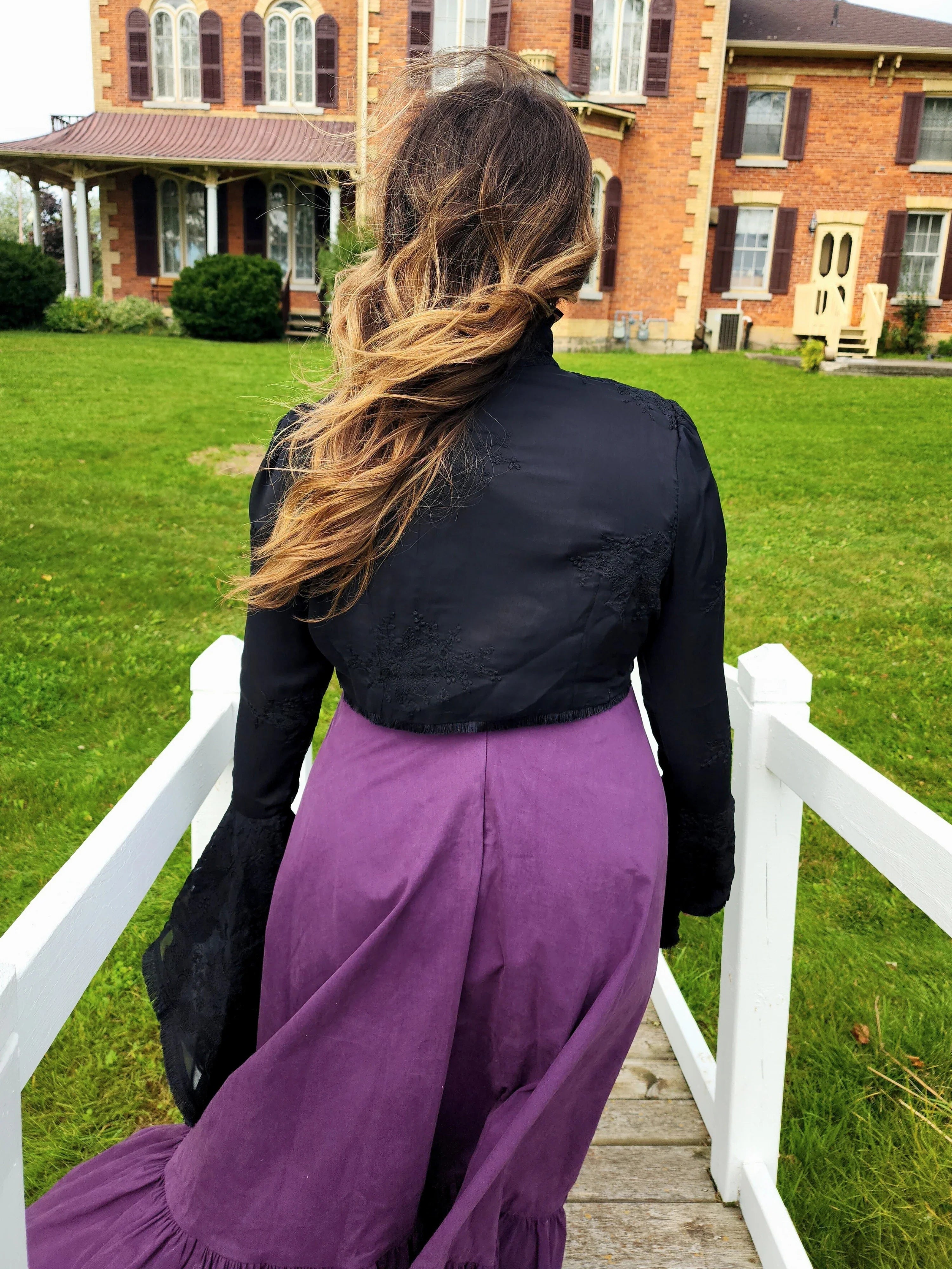 Woman in a black top and purple skirt showcasing the Lady Elizabeth jacket on a walkway