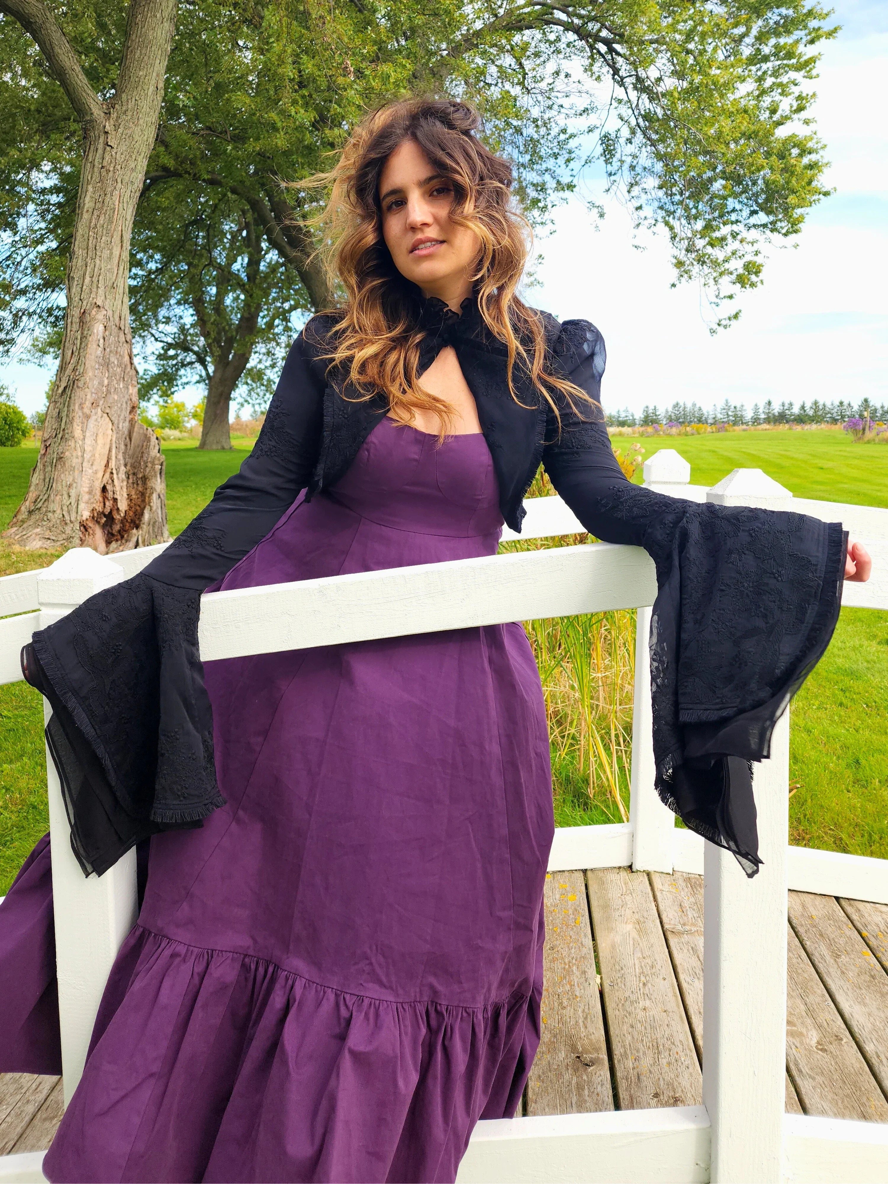 Woman in a purple dress and Lady Elizabeth jacket on a wooden deck