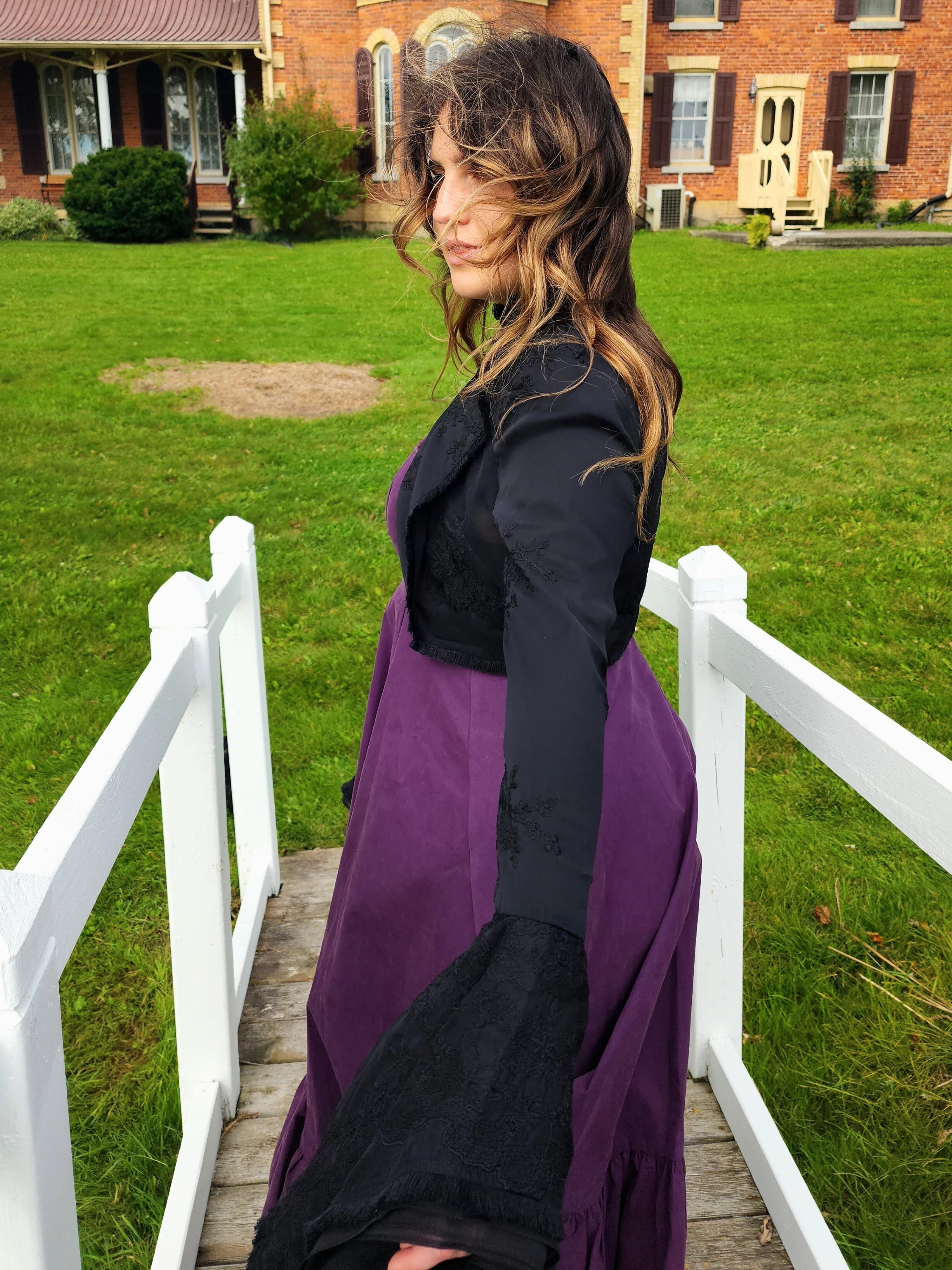 Woman in purple dress and black top showcasing the Lady Elizabeth jacket on a walkway