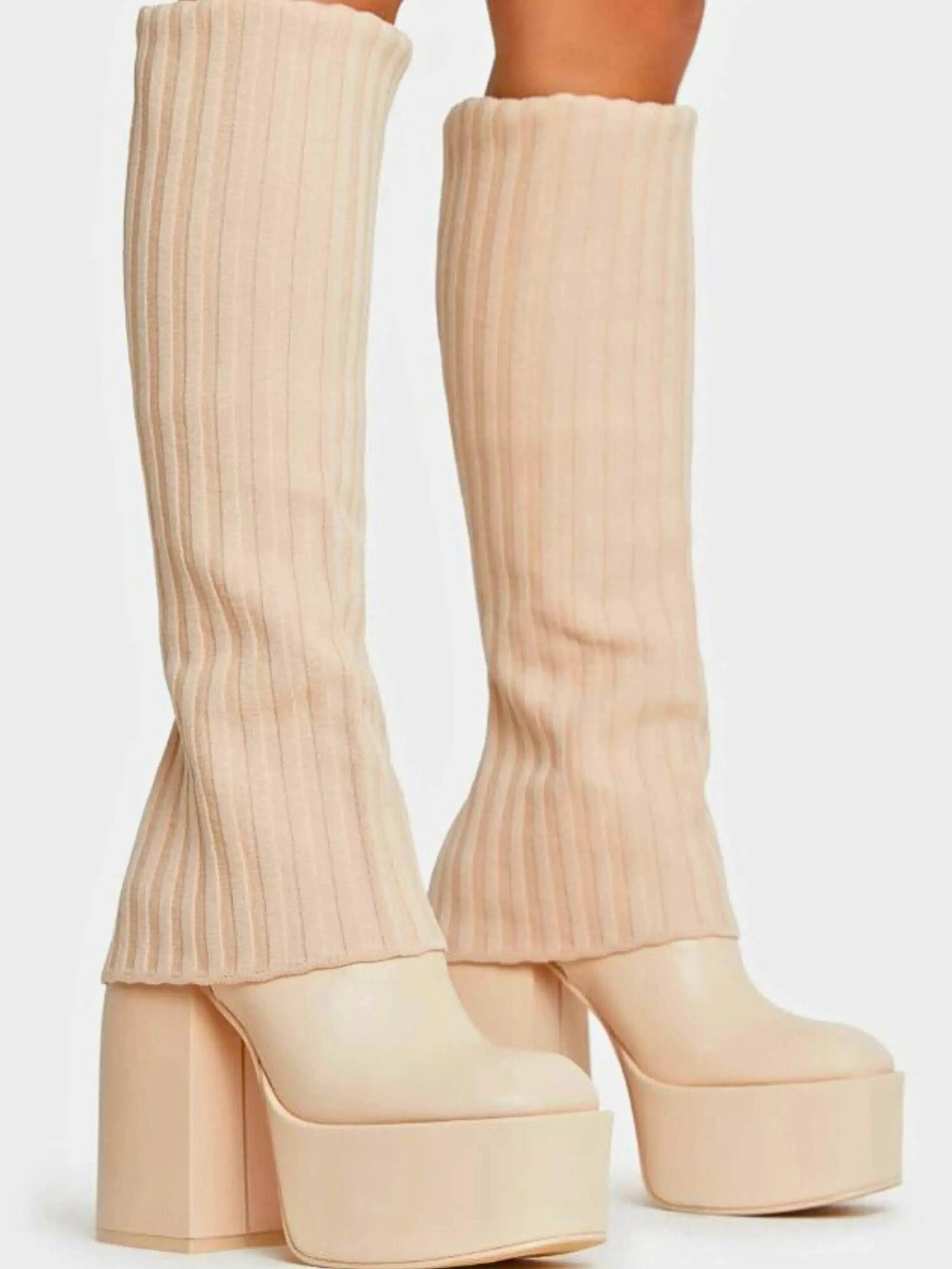 Cream-colored knee high platform boots with ribbed sock-style uppers and chunky heels.