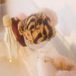 The leopard faux fur micro purse sitting in an empty champagne glass in a stylish setting.