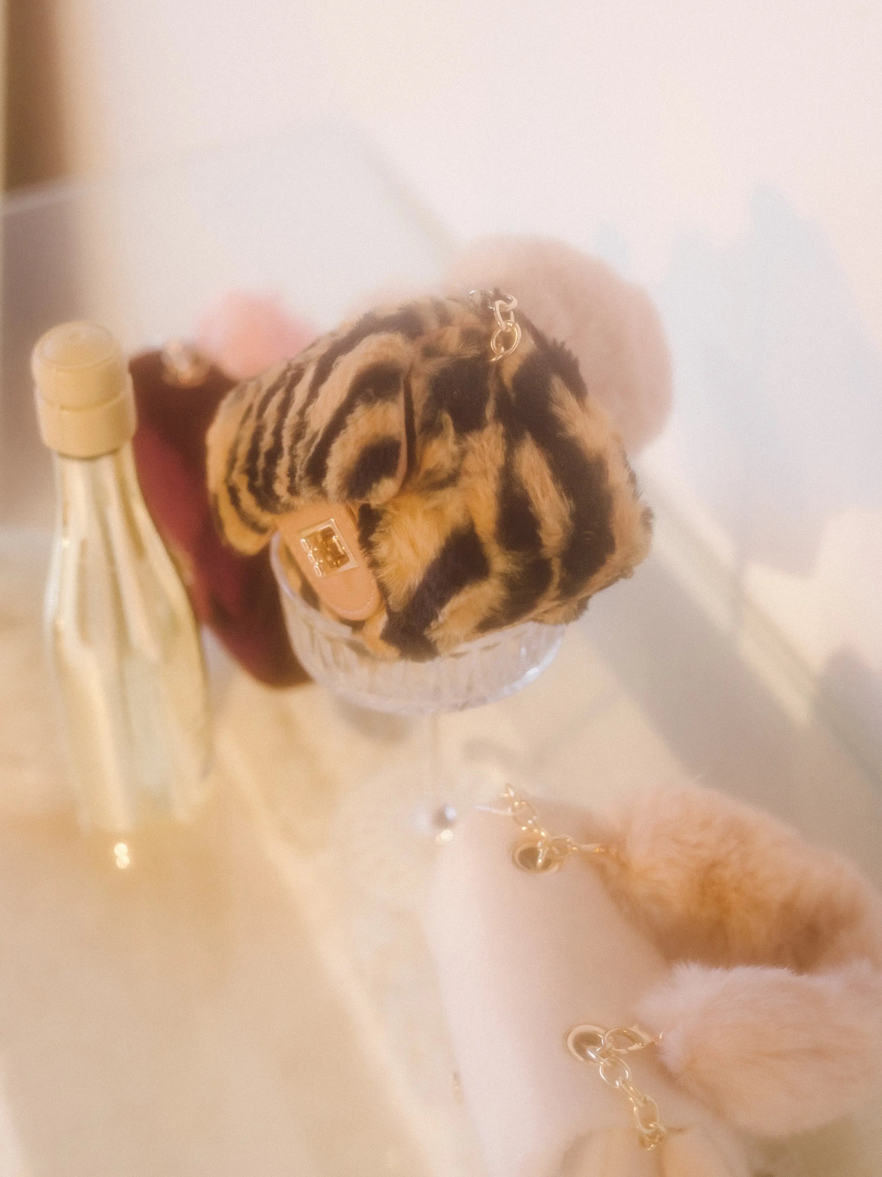 The leopard faux fur micro purse sitting in an empty champagne glass in a stylish setting.