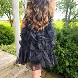 Long, wavy brown hair over a Ruffled Black Feather Mini Dress styled elegantly