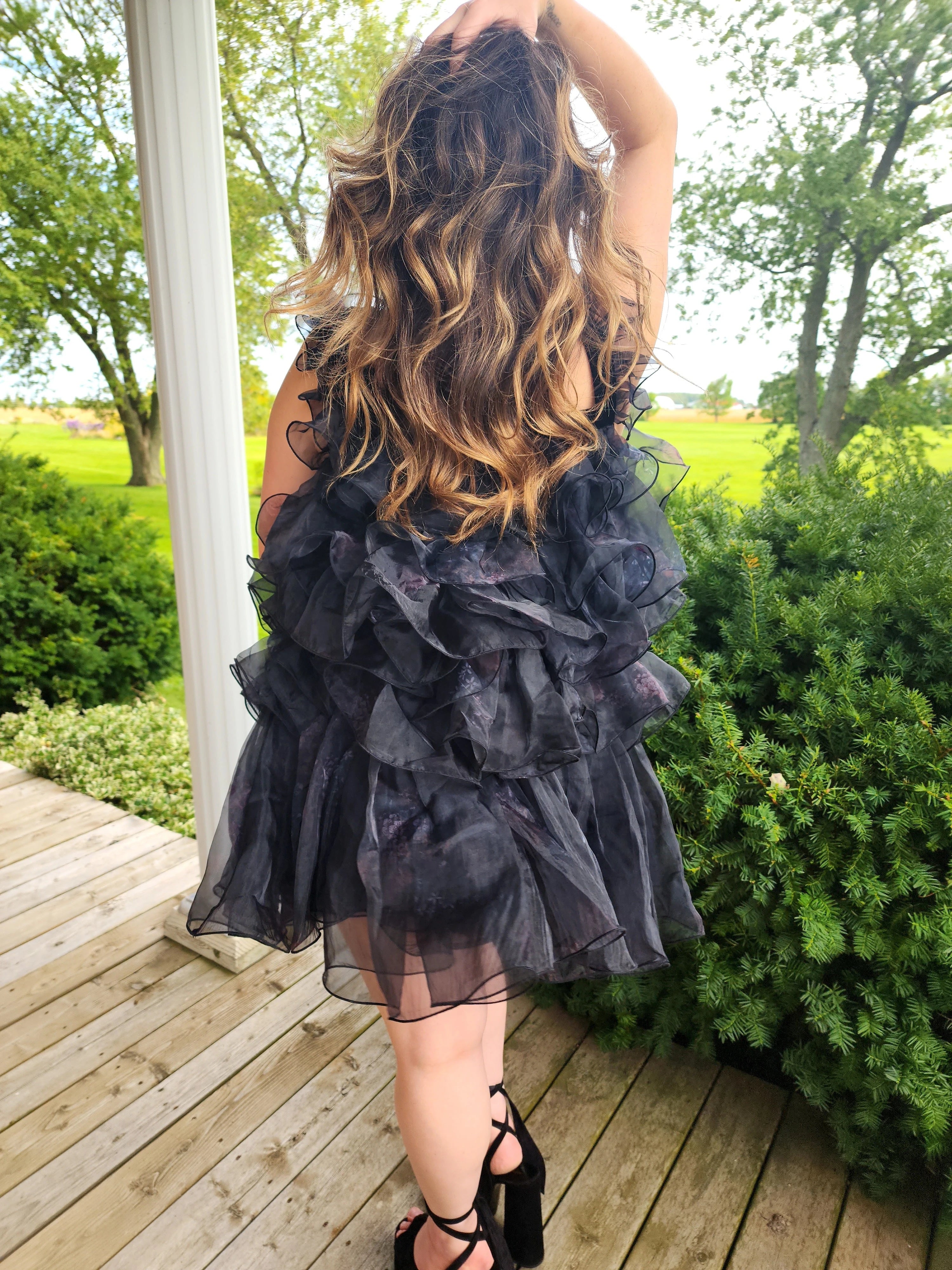 Long, wavy brown hair over a Ruffled Black Feather Mini Dress styled elegantly