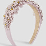 Lilac floral headband with gold accents on a light gray background.