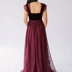 Back view of a red corset dress showing the square back and flowing chiffon skirt with a velvet bodice.
