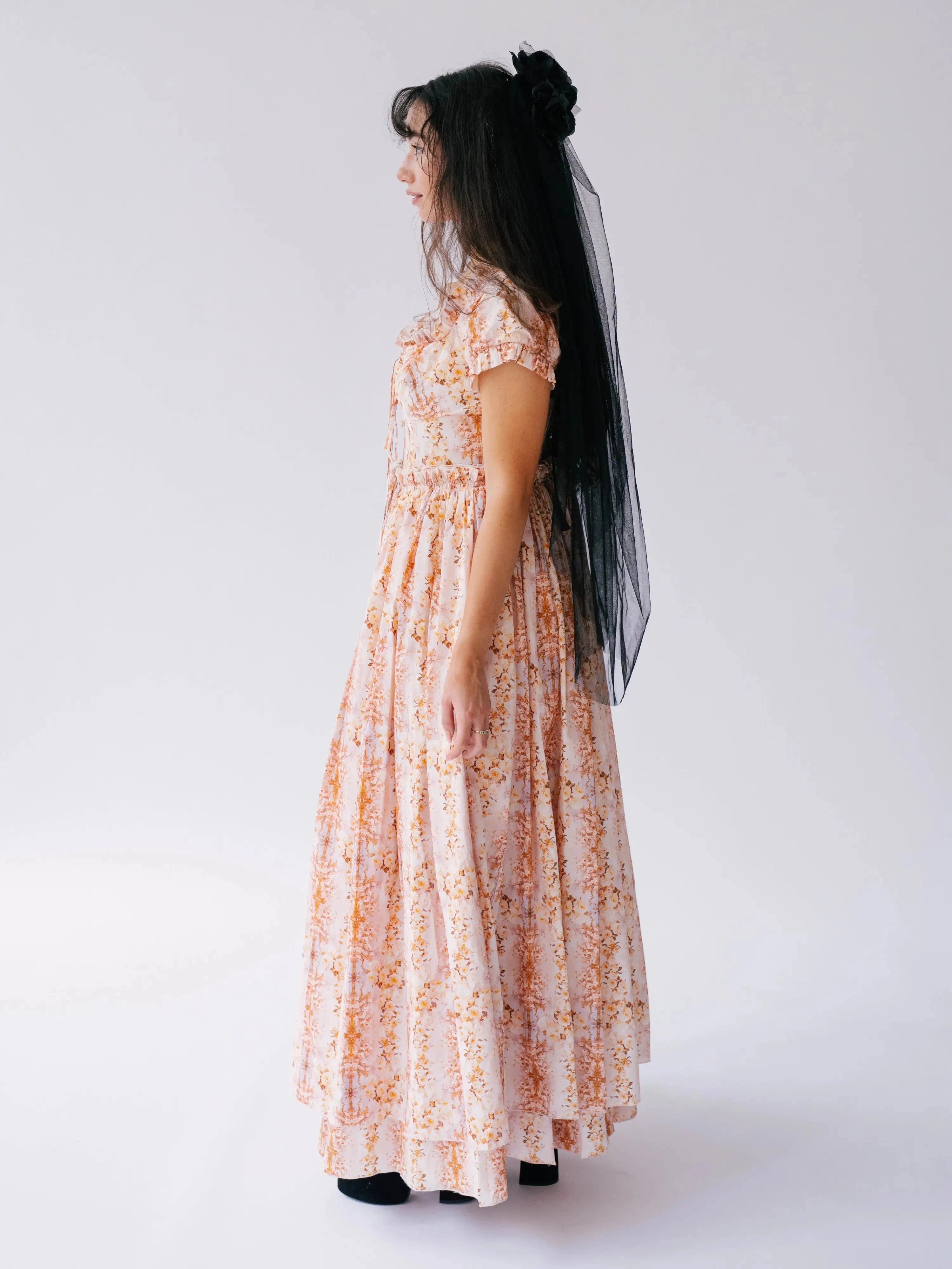 The twilight bloom meadow gown shown as a side profile view, showcasing the full-length silhouette and delicate floral pattern of this cotton gown.