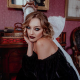 A woman wearing the Nocturne Velvet Mini Dress with a white lace hair bow in a vintage room.