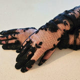 Elegant hand sewn opera gloves in black lace with floral patterns over nude fabric