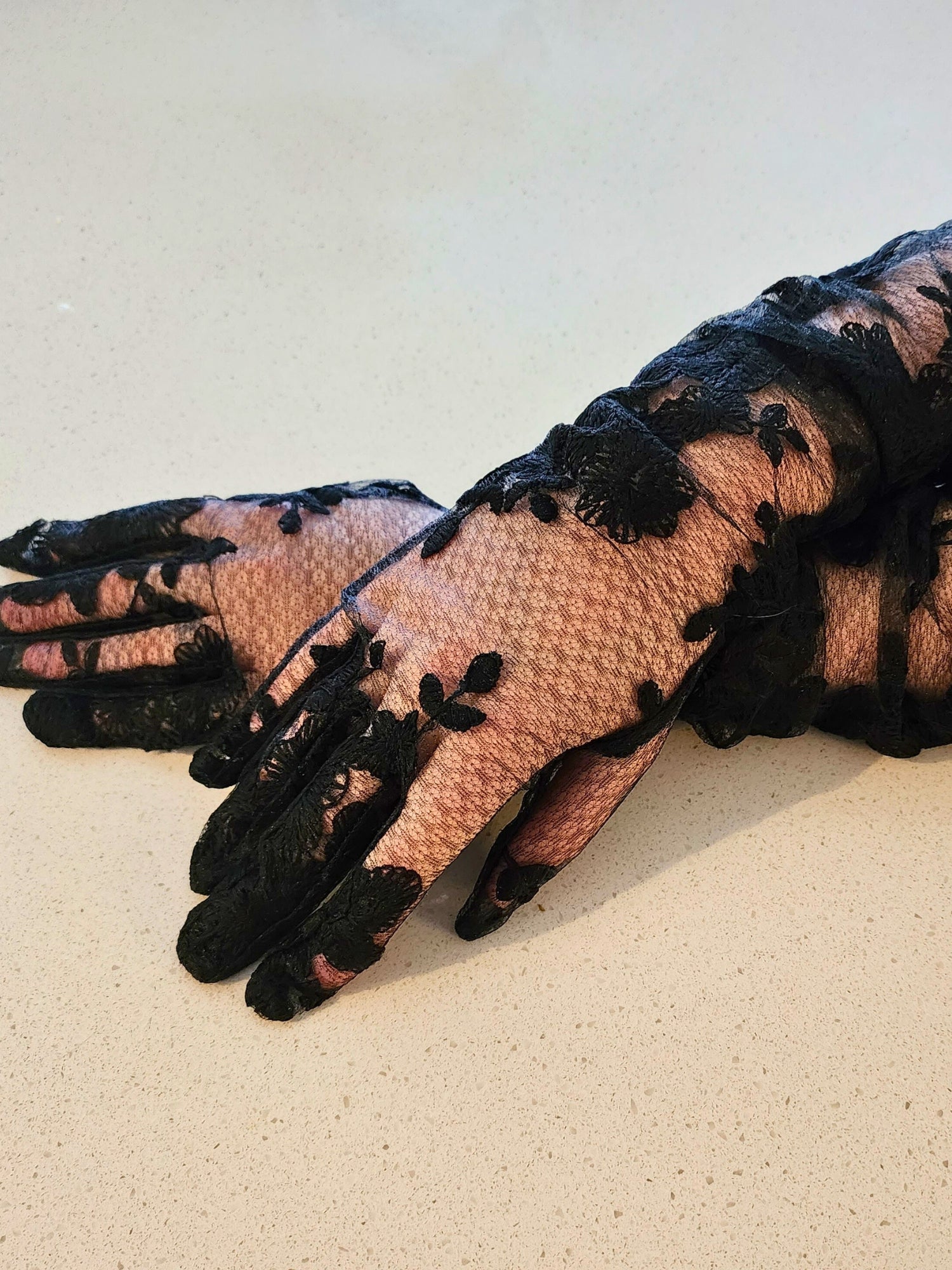 Elegant hand sewn opera gloves in black lace with floral patterns over nude fabric