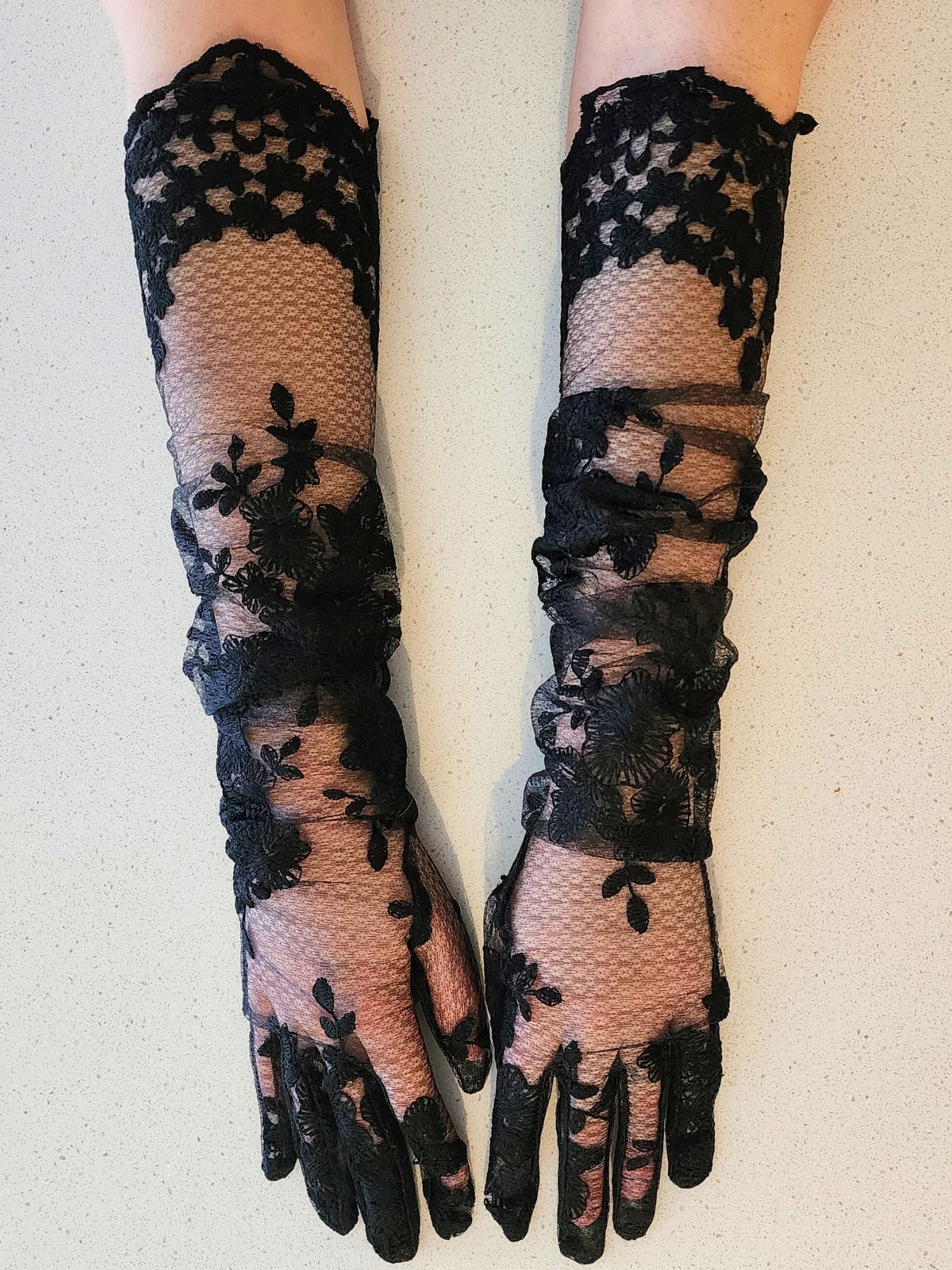 Hand sewn opera gloves in black lace elegantly covering hands and arms